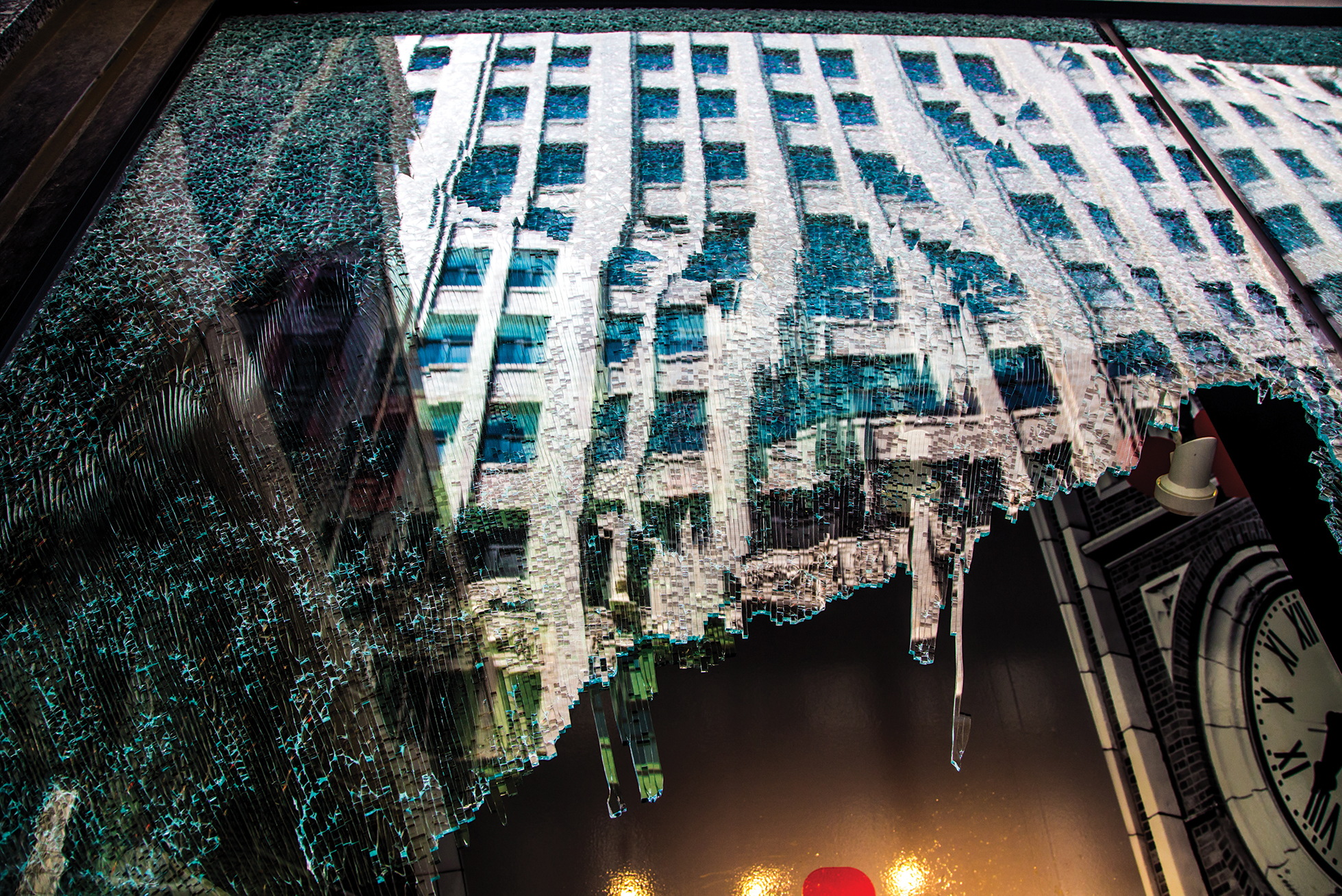 a broken window reflecting a building downtown