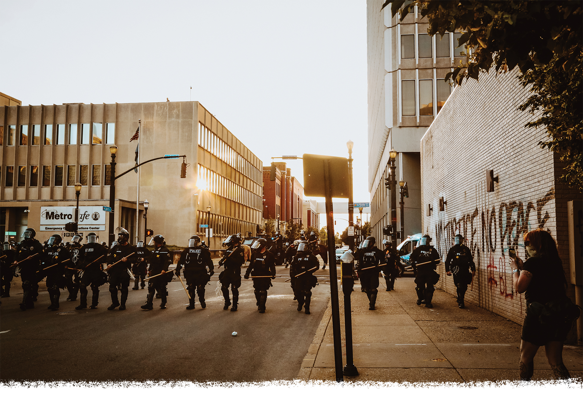 A line of police officers carrying clubs and sheilds advancing down the street.